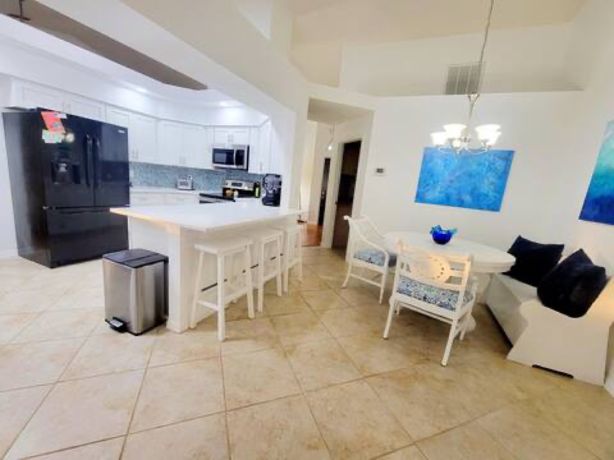 Kitchen with white cabinets, black fridge, breakfast area