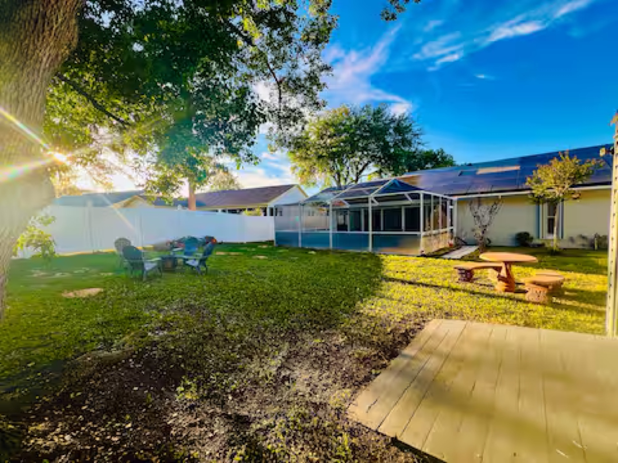 LARGE fenced backyard with rooftop solar panels covering the back of the house